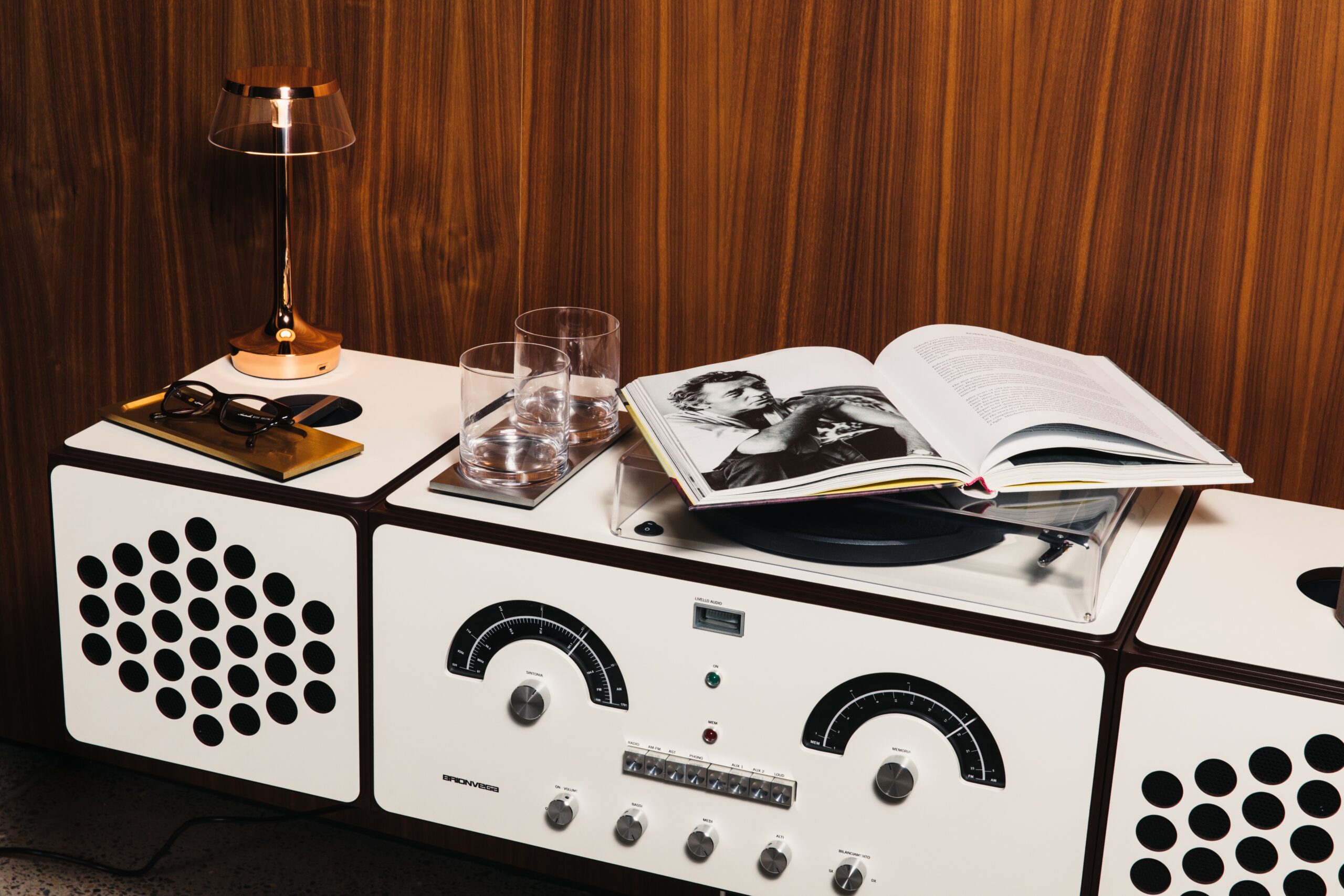 A high-angle detail shot of the handcrafted white Brionvega Radiofonografo RR226 console in a luxury lifestyle setting, featuring the iconic analogue dials and a Pro-Ject turntable integrated into the modular Italian cabinetry.