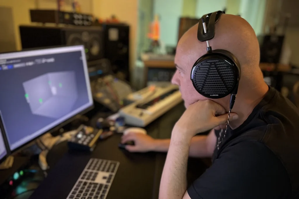 Producer and mixer David Kosten wearing Audeze planar magnetic headphones inside a professional music production studio.